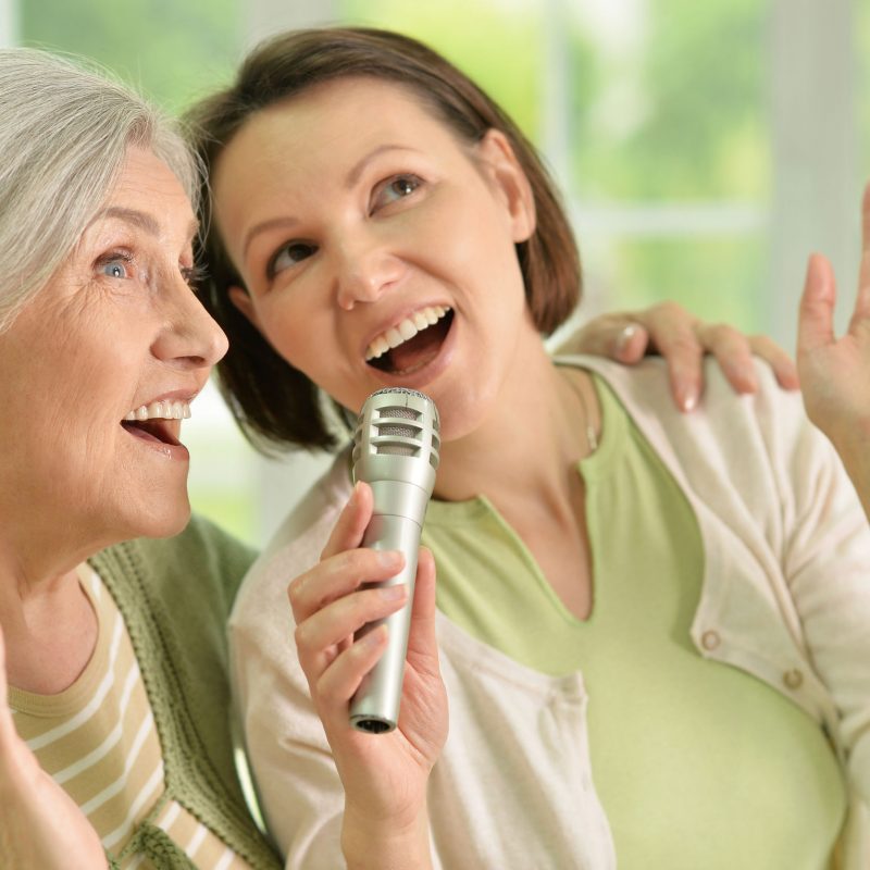 Portrait of Senior woman with daughter singing on microphone at home